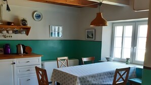 Uma área de refeições com mesa, cadeiras, bancada de cozinha e uma janela.