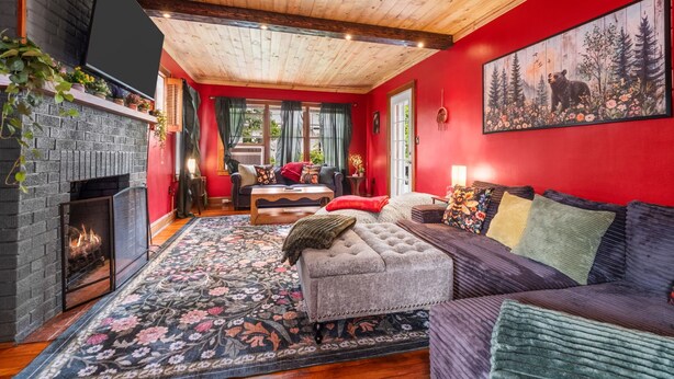 A cozy living room with a fireplace, a sofa, a coffee table, and a rug. - New! Hot Tub, Sauna, Arcade, cozy cottage - walk to everything! Great location! (Fayetteville)