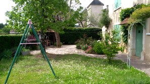 A garden with a stone pathway, a swing set, and a green door. - Beautiful Character House for 10 Guests with Large Private Pool (Lagardelle)