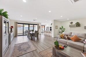 A modern living room with a sofa, a coffee table, and a dining area with chairs and a table. - Cabine Apartment | 3 bedrooms | Quarteira (Quarteira)