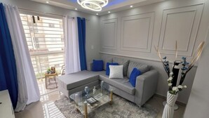 A modern living room with a grey sofa, a glass coffee table, and a fluffy rug.