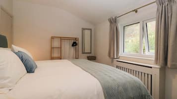 Un dormitorio con cama, ventana, radiador y espejo.