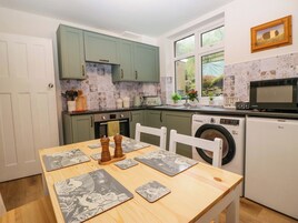 Una cocina funcional con una mesa de comedor, lavadora y microondas.