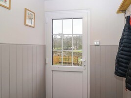 A room with a white door, a window, a wooden bench outside, and a coat rack.