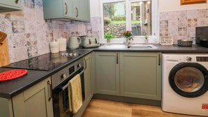 A kitchen with a washing machine, a window with a view, and a tiled backsplash. - Dakota (Holmrook)