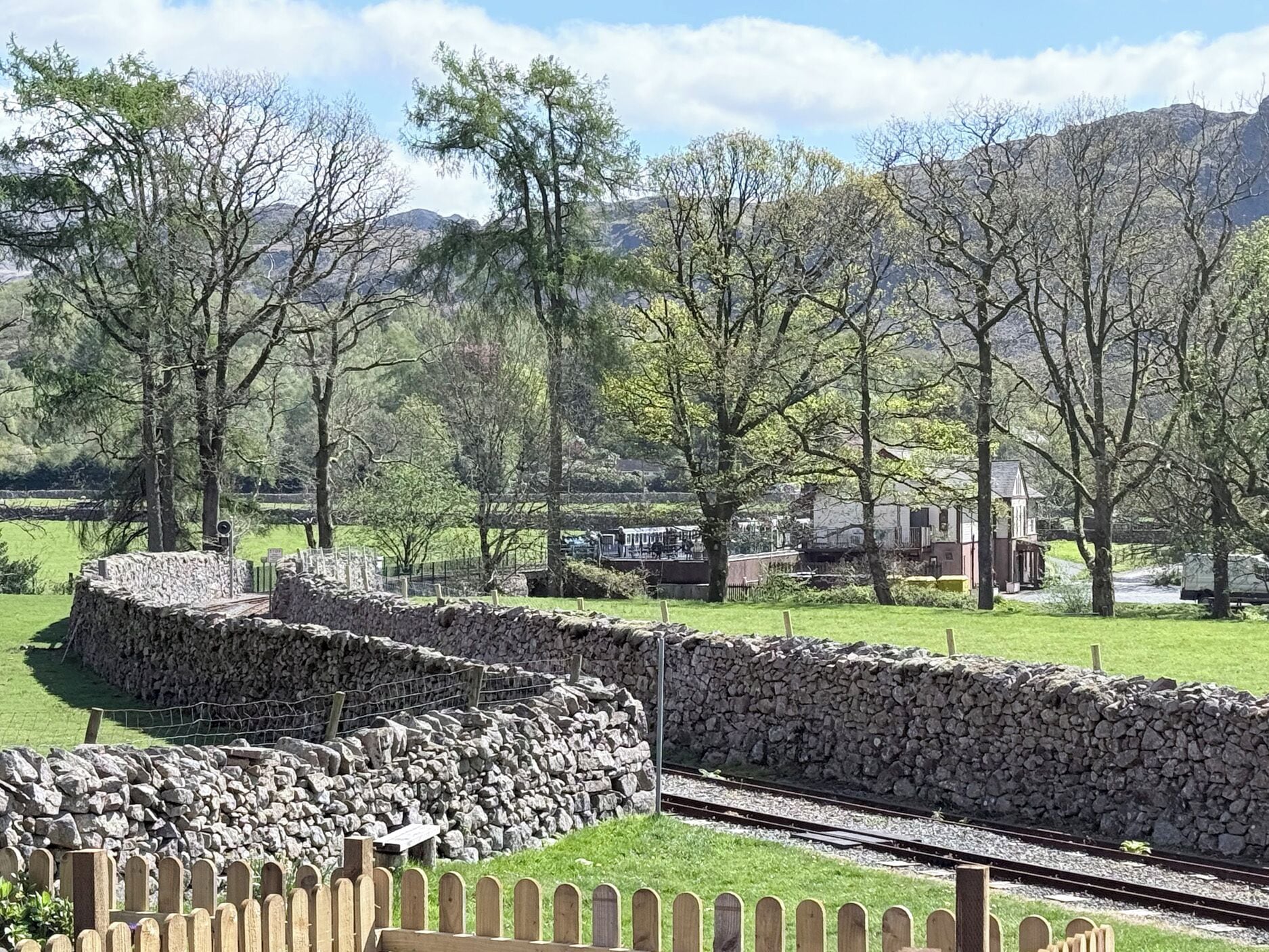 A stone wall, a wooden fence, and a railway track in a rural setting.