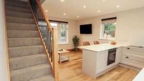 Une cuisine moderne dotée d’un îlot central, d’un plancher en bois et d’un escalier avec une rampe en bois.