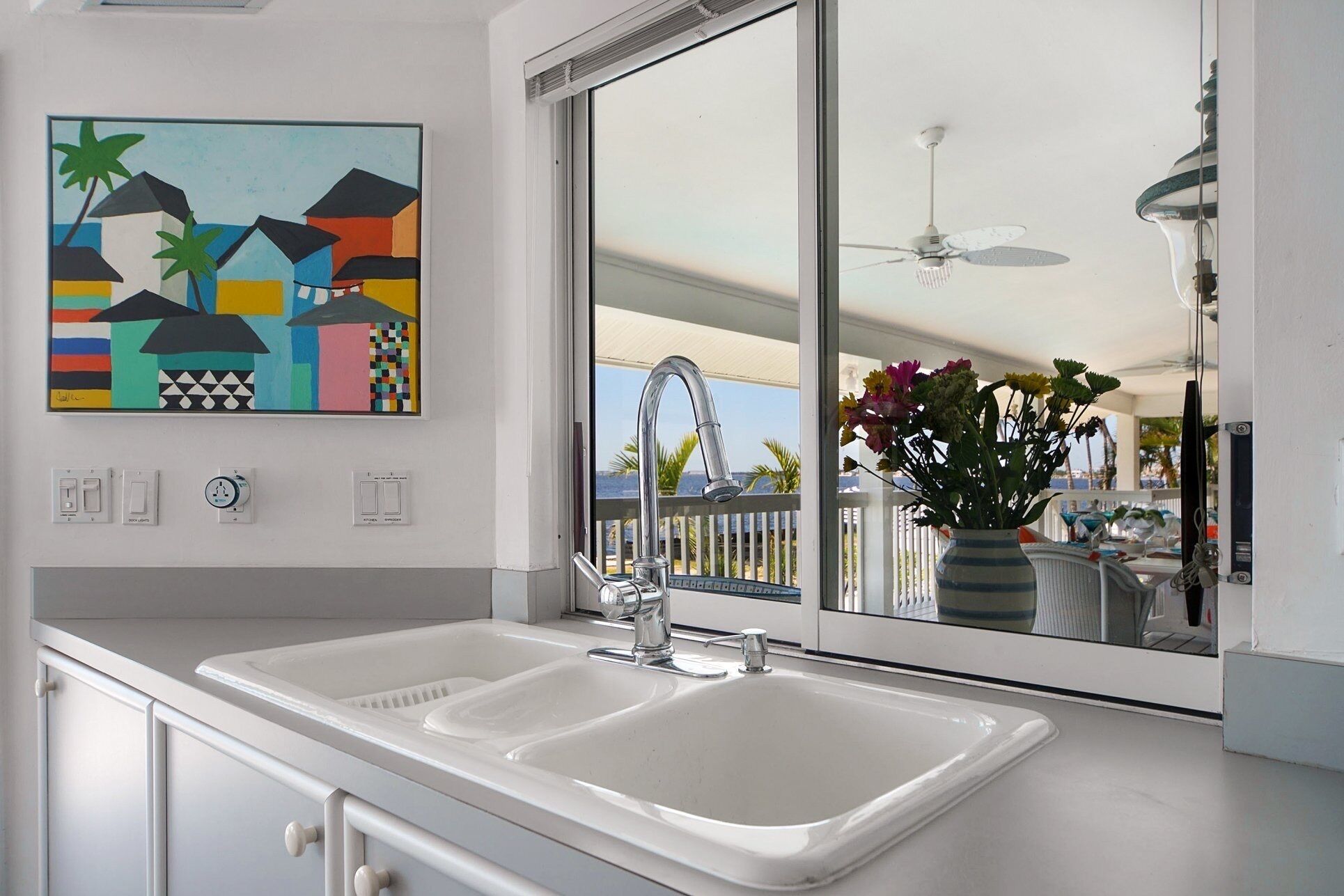 A modern kitchen with a large window, a painting, and a view of the ocean.