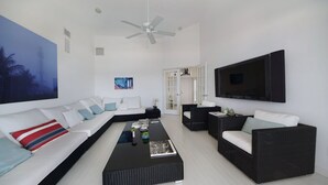 A modern living room with a sofa, coffee table, and a TV mounted on the wall. - Villa Southern Living, dreamy waterfront vacation home in Cape Coral (Cape Coral)