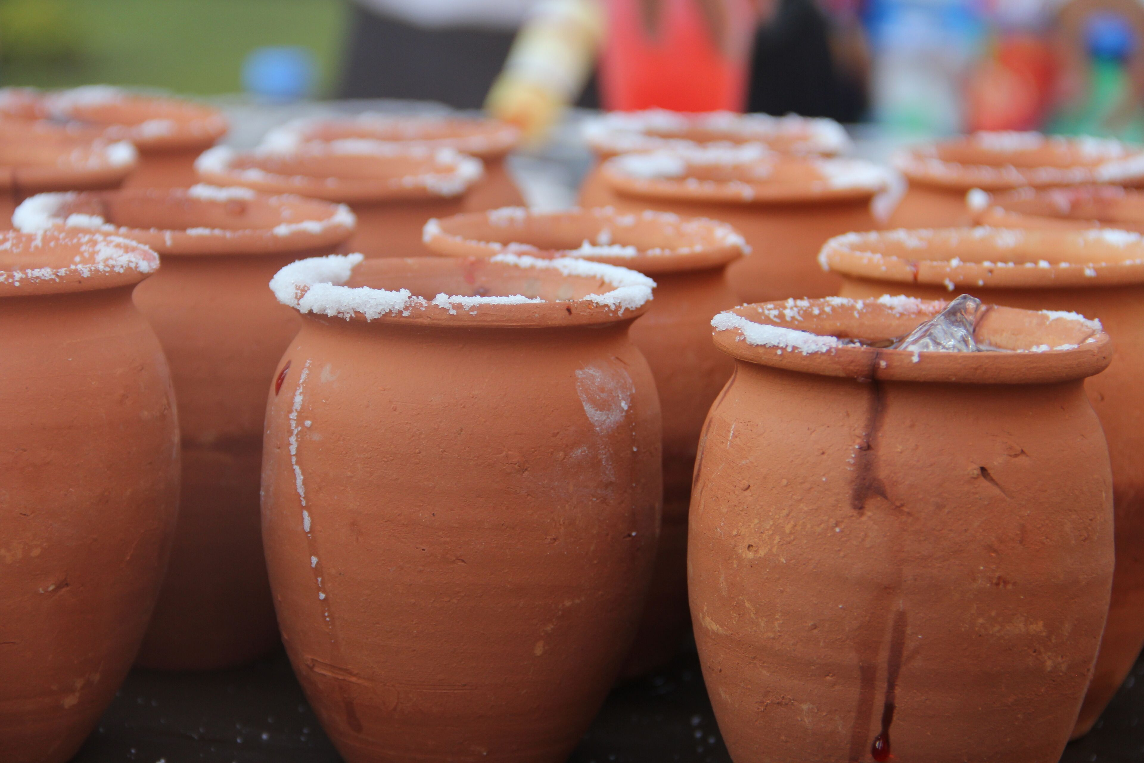 Terracotta pots with white sugar on top, arranged closely together.