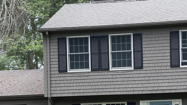 A two-story house with a front porch, a blue door, and a well-maintained garden.