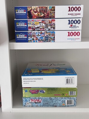Hylly, jossa on kolme kirjaa ja lautapeli.