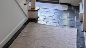A staircase with wooden balusters, a door with a glass panel, and a stone-tiled floor.