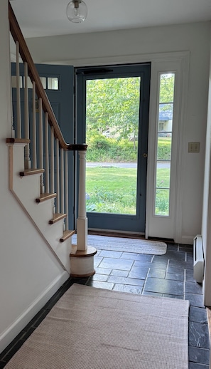 A staircase with wooden balusters, a door with a glass panel, and a stone-tiled floor. - Wonderful 4-bedroom house in Kingston perfect for families.. (South Kingstown)