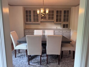 A dining area with a dark wooden table, four upholstered chairs, and a hanging light fixture. - Wonderful 4-bedroom house in Kingston perfect for families.. (South Kingstown)