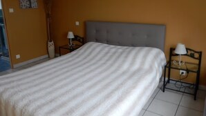 A hotel room with a large bed, two bedside tables with lamps, a headboard, and a wall with artwork. - Bed and Breakfast 'Chambre Orange' with Shared Garden and Wi-Fi (Courtils)