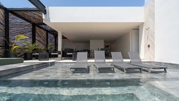 A modern outdoor pool area with lounge chairs, a covered seating area, and a clear pool. - Maria Tulum - Modern 2BR Retreat with Pool (Tulum)