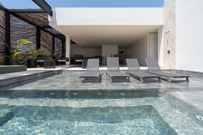 A modern outdoor pool area with lounge chairs, a covered seating area, and a clear pool. - Maria Tulum - Modern 2BR Retreat with Pool (Tulum)