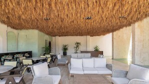 A lounge area with wicker furniture, a thatched ceiling, and potted plants. - Maria Tulum - Modern 2BR Retreat with Pool (Tulum)