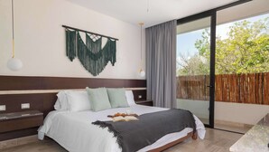 A modern bedroom with a large bed, a nightstand, a wall-mounted macrame piece, and a sliding glass door to a balcony. - Maria Tulum - Modern 2BR Retreat with Pool (Tulum)
