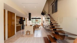 Een modern interieur met een trap, houten vloeren en een keukenhoek.