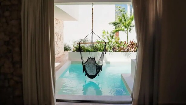 En hængekøje over en pool med udsigt til grøn vegetation og en stenv æg.
