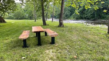 A picnic table in a grassy area with trees and a river in the background.