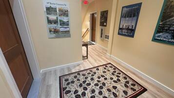 A hallway with a wooden floor, a patterned rug, and several posters on the walls.