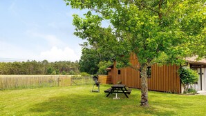 A wooden cabin with a picnic table and grill, surrounded by a grassy yard and trees. - Cosy Rural Cottage "Bergerie Couyrasseau" 1-5 Guests - Carcans - Wifi - Vacation/Remote Work (Carcans)