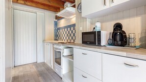 A kitchen with white cabinets, a microwave, a coffee maker, and a clock on the wall. - Cosy Rural Cottage "Bergerie Couyrasseau" 1-5 Guests - Carcans - Wifi - Vacation/Remote Work (Carcans)
