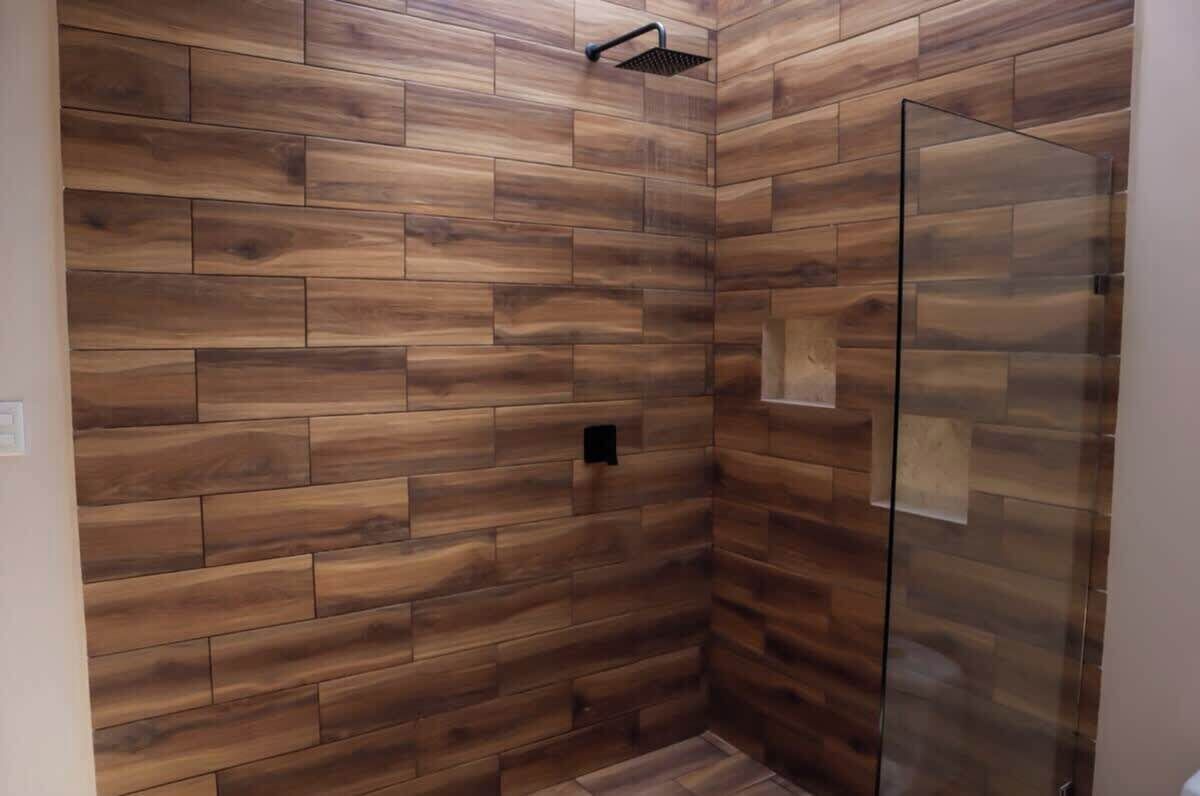 A shower area with wooden panel walls and a glass shower enclosure.