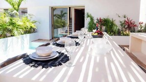 An outdoor dining area with a table set for two, surrounded by lush greenery and a view of a pool. - Huge 10BR Luxury Villa Complex w/ 6 Private Pool (Tulum)