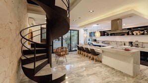 Una cocina moderna con piso de mármol, una isla central y una escalera de caracol.
