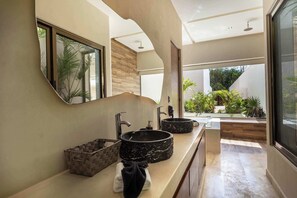 A modern bathroom with a large mirror, two sinks, and a view of a garden. - Chic 6BR Dual villa with 4 Private Pools-Concierge (Tulum)