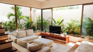 Uma sala de estar moderna com sofá, televisão e plantas em vasos.