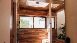 Um corredor com lambris de madeira, uma janela grande e uma planta.