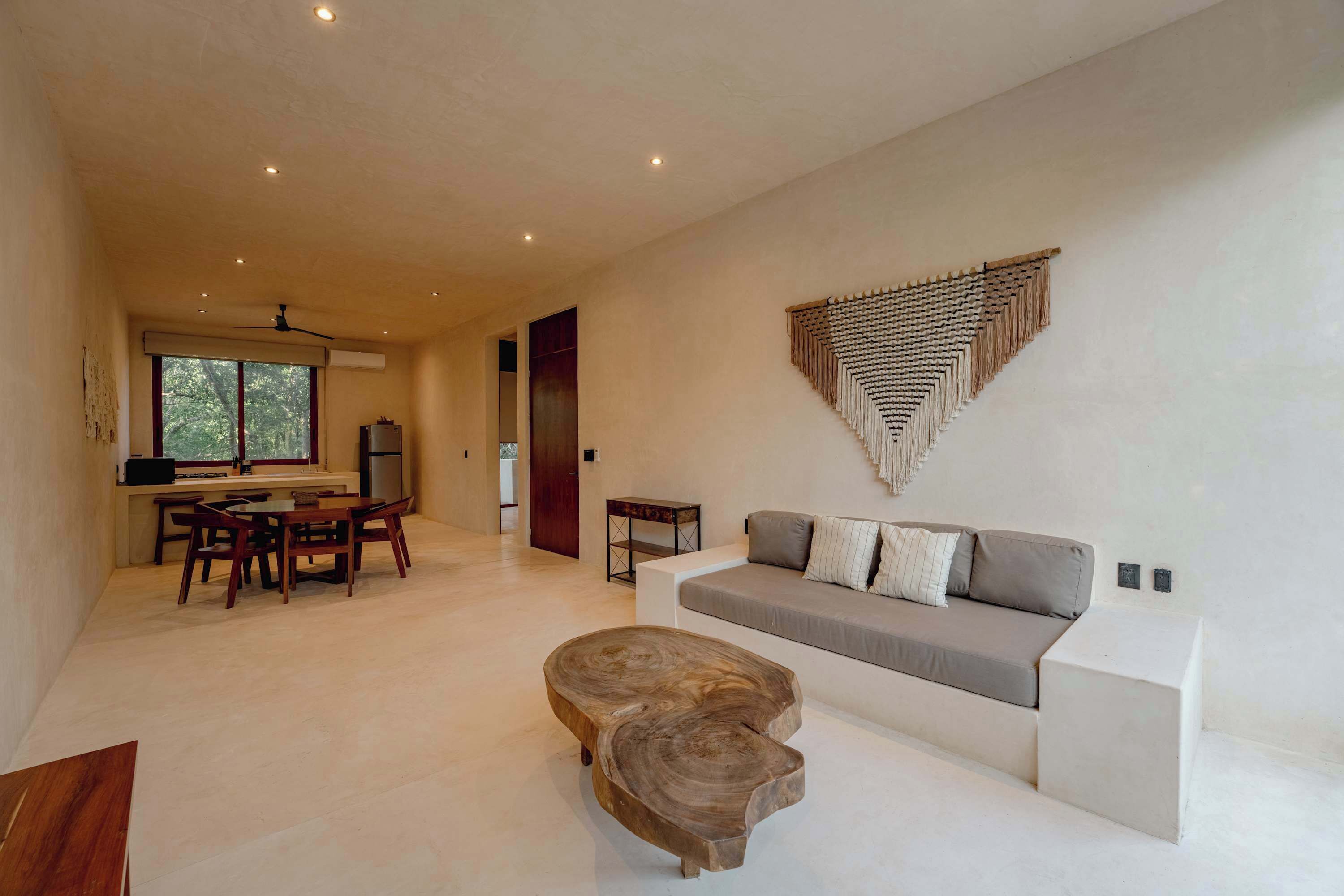 A modern living room with a sofa, a wooden coffee table, and a dining area with chairs and a table.