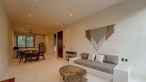 Una sala de estar moderna con un sofá, una mesa de centro de madera y un comedor con sillas y una mesa.
