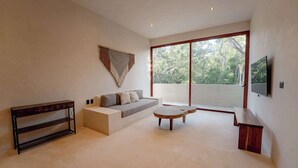 Una sala de estar moderna con un sofá, una mesa de centro, una consola de madera y un televisor montado en la pared.