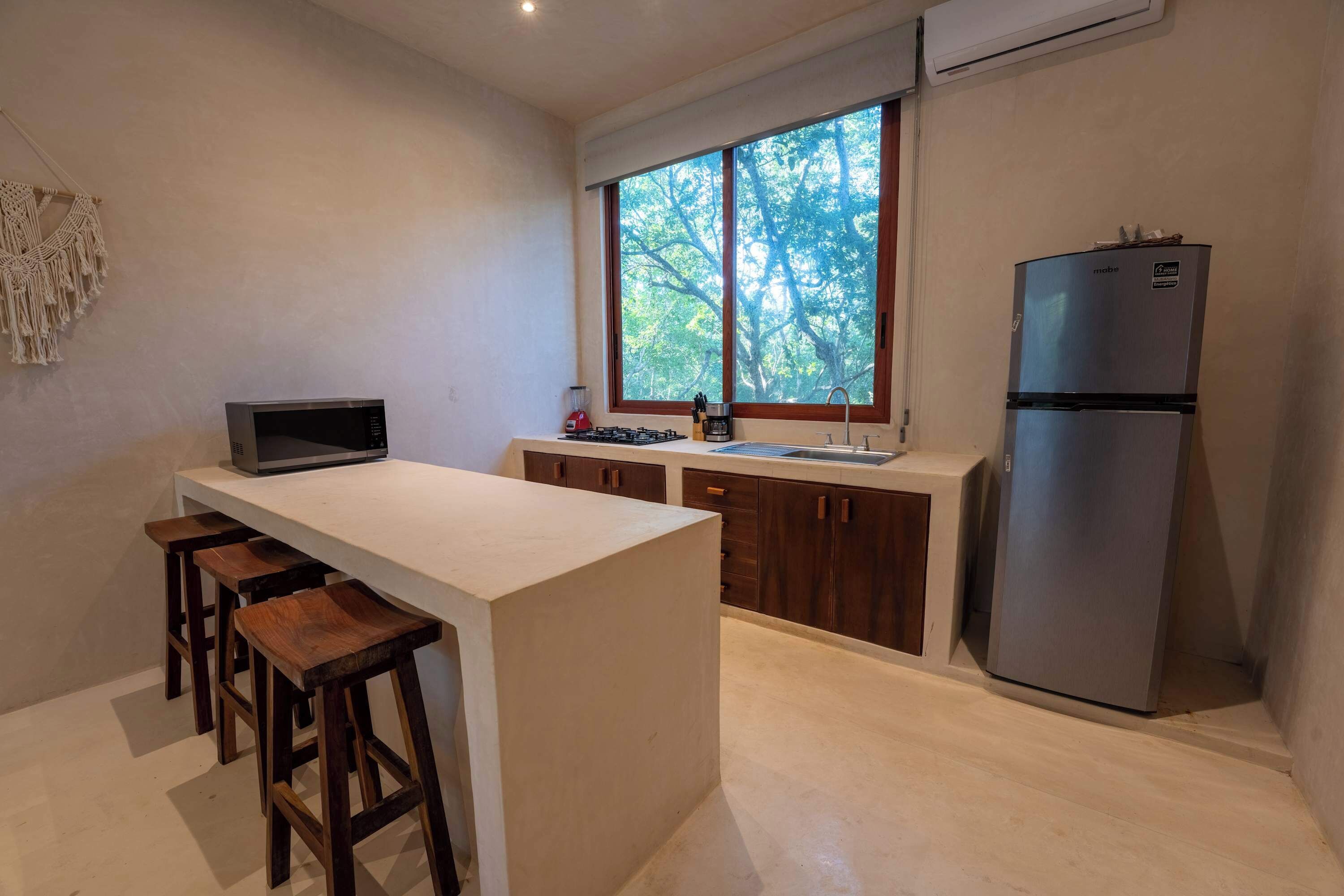 Eine moderne Küche mit einer zentralen Kochinsel, Barhocker, einer Mikrowelle, einem Spülbecken und einem Kühlschrank.