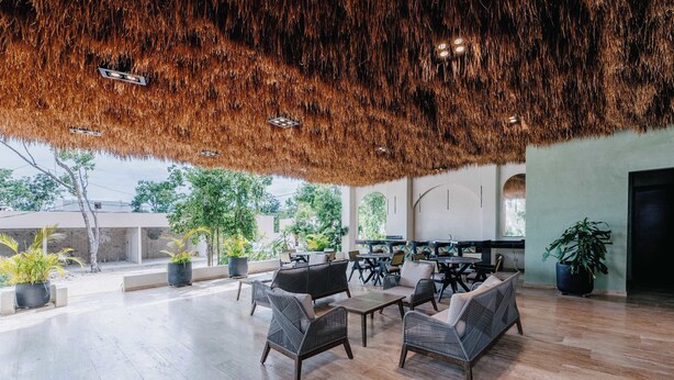 An open-plan lounge with wicker furniture, a thatched ceiling, and potted plants. - Luxury Penthouse Private Rooftop Pool Concierge (Tulum)