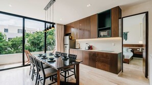 A modern kitchen with a dining area, large windows, and a view of greenery. - Luxury Penthouse Private Rooftop Pool Concierge (Tulum)