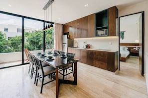 A modern kitchen with a dining area, large windows, and a view of greenery. - Luxury Penthouse Private Rooftop Pool Concierge (Tulum)