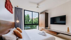 A modern hotel room with a large bed, a TV, and a view of greenery outside. - Luxury Penthouse Private Rooftop Pool Concierge (Tulum)