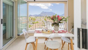 A balcony with a table set for two, a vase with flowers, and a view of a mountain and buildings. - Bella View of Magestic Table Mountain (Cape Town)