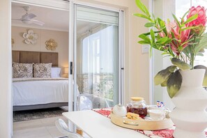 A bedroom with a bed, a sliding glass door to a balcony, and a breakfast tray on a table. - Bella View of Magestic Table Mountain (Cape Town)