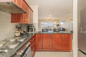 A kitchen with wooden cabinets, a granite countertop, and a view of the outdoors. - Bella View of Magestic Table Mountain (Cape Town)