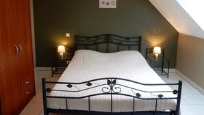 Une chambre à coucher avec un lit, deux lampes de chevet, une armoire en bois et un panneau fixé au mur.