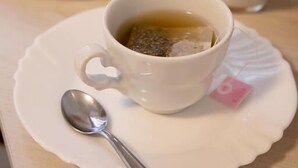 Une table avec une tasse de thé, une assiette de croissants et un verre de jus d’orange.