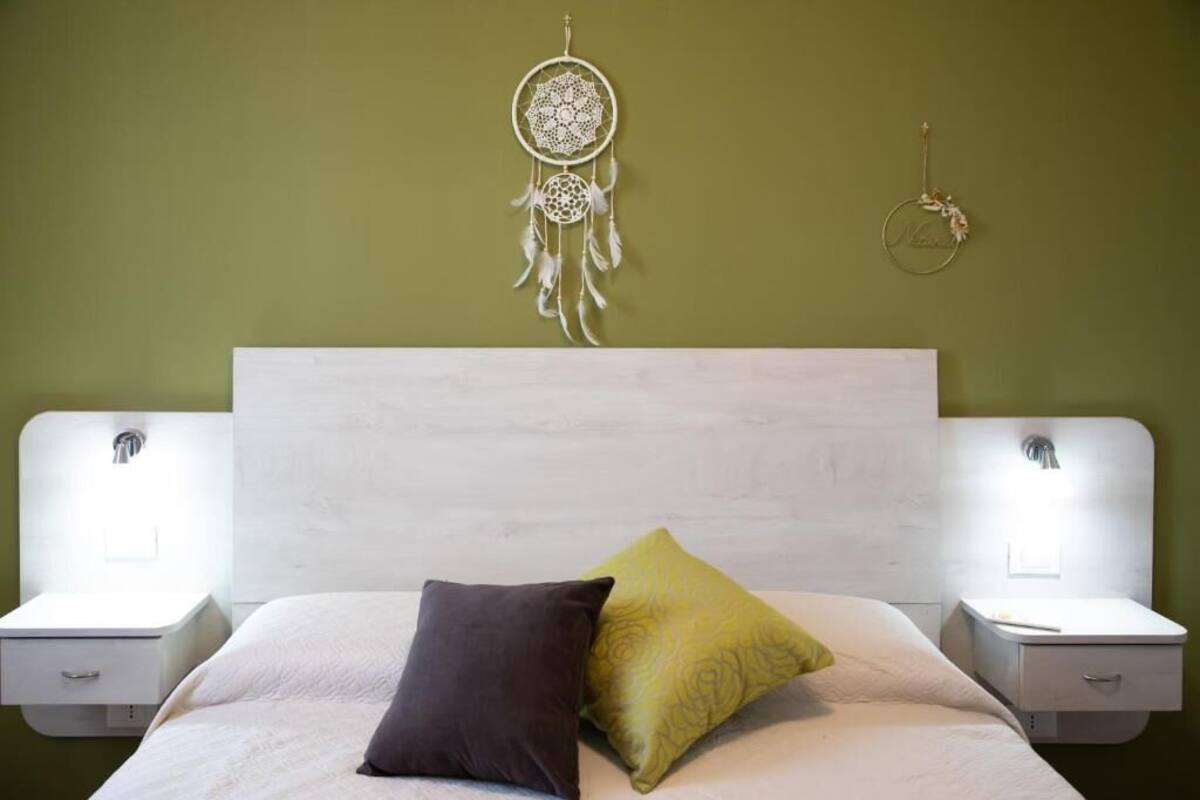 A bed with two pillows, a white headboard, and bedside tables with lamps.